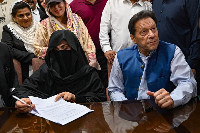 Pakistan’s former Prime Minister, Imran Khan (R) along with his wife Bushra Bibi (L) looks on as he signs surety bonds for bail in various cases, at a registrar office in the High court, in Lahore on 17 July, 2023