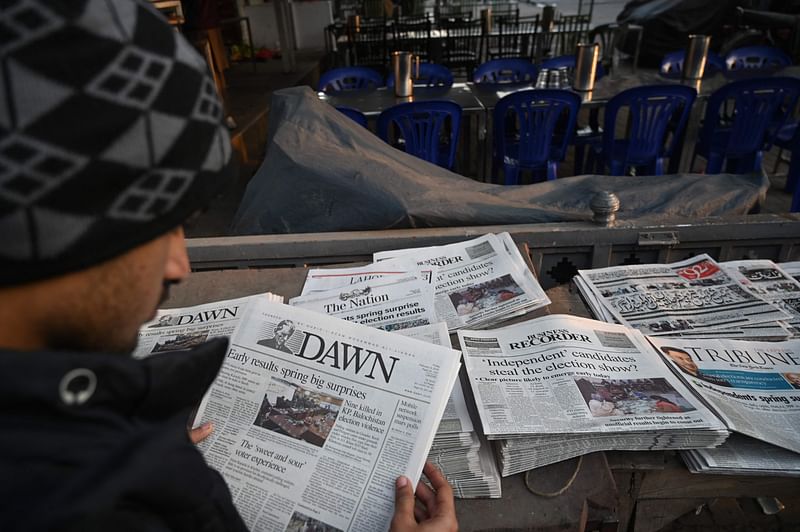 A man reads morning newspapers with the front page election headlines along a roadside stall a day after Pakistan's national general election in Lahore on 9 February, 2024