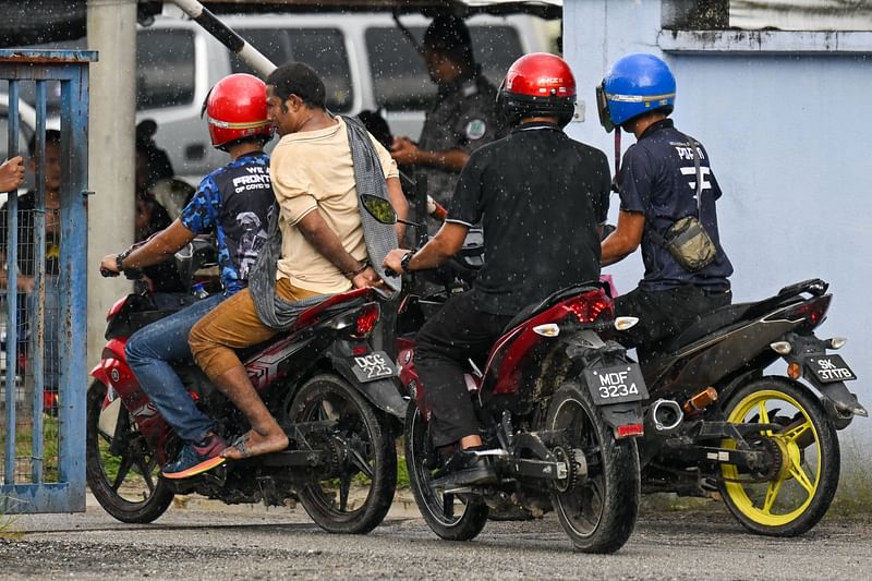 Malaysian authorities escort a handcuffed detainee (2nd L) into the immigration detention centre in Bidor in Malaysia’s northern Perak state on 2 February, 2024, after more than 100 Rohingya refugees escaped the facility