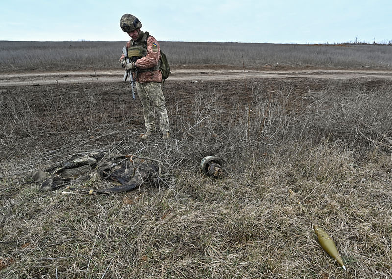 A Ukrainian serviceman of the 65th Mechanised Brigade of the Ukrainian Armed Forces inspects remains of the body of a Russian soldier near the front line village of Robotyne, amid Russia's attack on Ukraine, in Zaporizhzhia region, Ukraine 21 February 2024