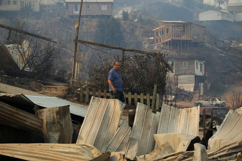 A man stands near the remains of burnt houses following the spread of wildfires in Vina del Mar, Chile February 3, 2024