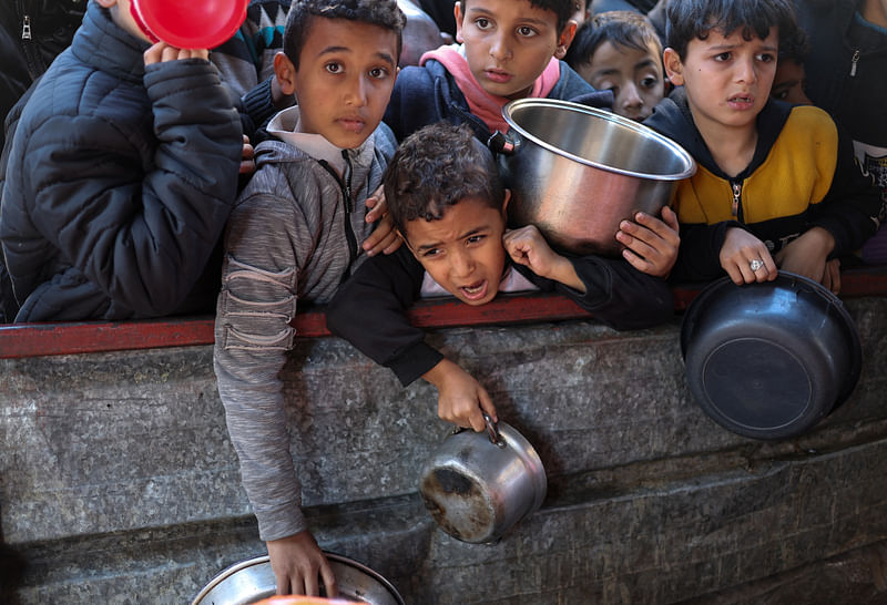 Palestinian children wait to receive food cooked by a charity kitchen amid shortages of food supplies, as the ongoing conflict between Israel and the Palestinian Islamist group Hamas continues, in Rafah, in the southern Gaza Strip, February 5, 2024