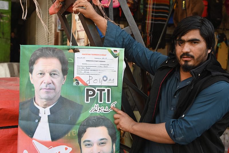 A vendor holds the poster with a portrait of Pakistan’s jailed former prime minister Imran Khan, at a market in Lahore on 9 February, 2024, a day after Pakistan's national elections