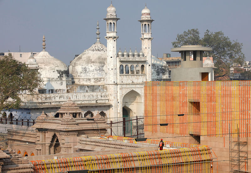 A worker stands on a temple rooftop adjacent to the Gyanvapi Mosque in the northern city of Varanasi, India, December 12, 2021