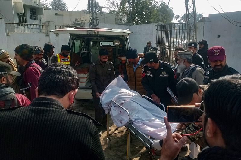 Graphic content / Policemen shift the body of a colleague who was killed in an attack on a police station, at a hospital in Dera Ismail Khan on February 5, 2024