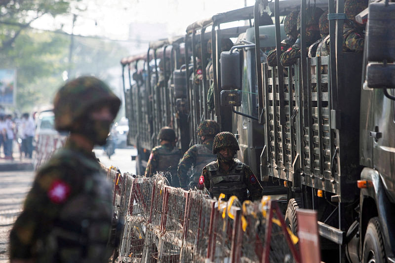 Soldiers stand next to military vehicles as people gather to protest against the military coup, in Yangon, Myanmar, on 15 February, 2021