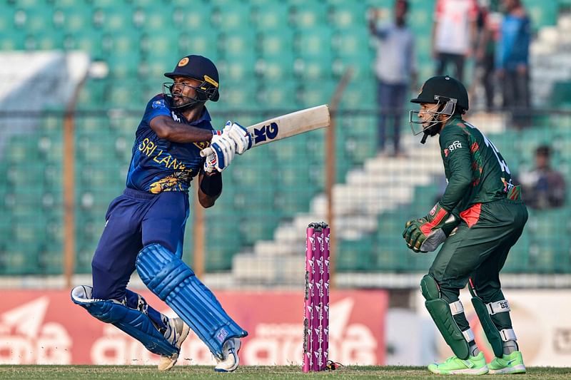 Sri Lanka's Janith Liyanage plays a shot as Bangladesh's Mushfiqur Rahim (R) watches during the first one-day international (ODI) cricket match between Bangladesh and Sri Lanka at the Zahur Ahmed Chowdhury Stadium in Chittagong on March 13, 2024.