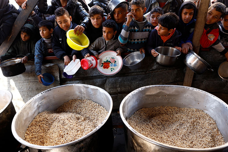 Palestinian children wait to receive food cooked by a charity kitchen amid shortages of food supplies, as the ongoing conflict between Israel and the Palestinian Islamist group Hamas continues, in Rafah, in the southern Gaza Strip, 5 February, 2024.