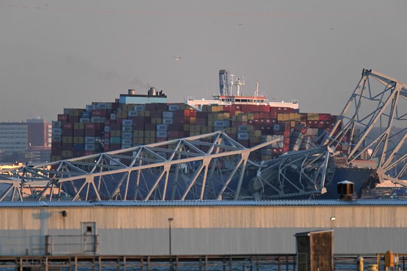 The steel frame of the Francis Scott Key Bridge sits on top of a container ship after it struck the bridge in Baltimore, Maryland, on 26 March 2024.