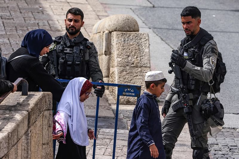 Members of the Israeli security forces stand guard as Muslim worshippers pass through a checkpoint near Lion's Gate in Jerusalem, to enter the Al-Aqsa Mosque compound for the Friday noon prayer, on 1 March  2024 amid the ongoing battles between Israel and the Palestinian group Hamas.