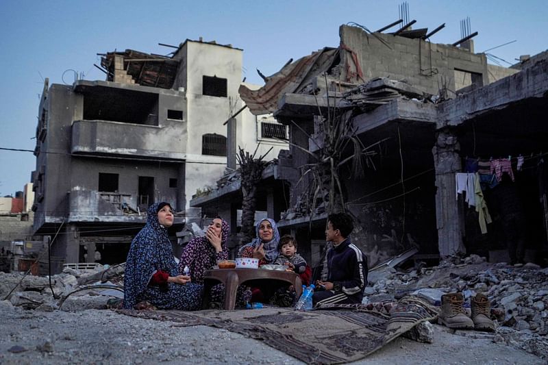 The Palestinian Al-Naji family eats an iftar meal, the breaking of fast, amidst the ruins of their family house, on the first day of the Muslim holy fasting month of Ramadan, in Deir el-Balah in the central Gaza Strip on 11 March  2024, amid ongoing battles between Israel and the militant group Hamas.