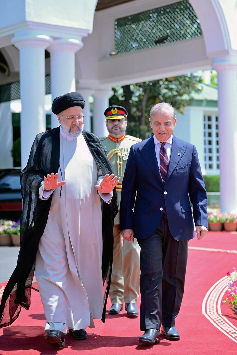 This handout photograph taken and released by Pakistan Prime Minister's Office on 22 April 2024 shows Iran’s President Ebrahim Raisi (L) walking along with Pakistan's Prime Minister Shehbaz Sharif (R) to inspect his guard of honour, in Islamabad.