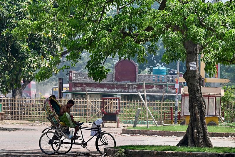 A cycle-rickshaw puller takes a break under the shade of a tree to shelter from the heat on a summer afternoon in Dhaka on 29 April, 2024