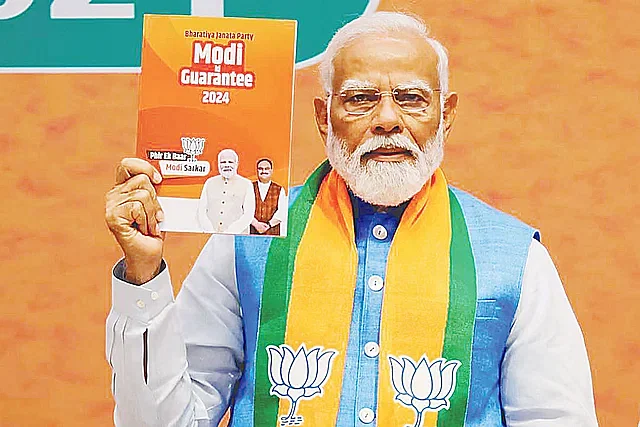 Narendra Modi holds up the BJP election manifesto