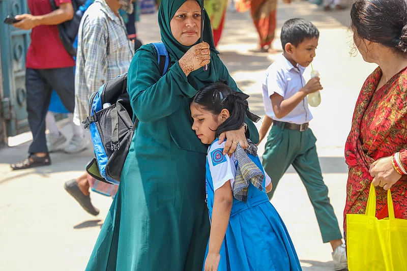 Amid the sweltering heat, a woman takes her daughter under the shade of an umbrella immediate after the school ends in Lakshmibazar, Dhaka