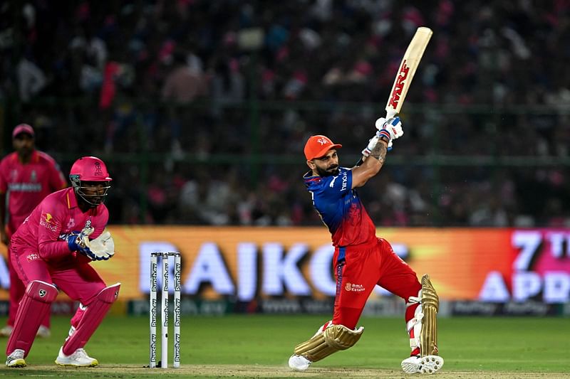 Virat Kohli plays a shot as Rajasthan Royals' wicketkeeper and captain Sanju Samson watches during the Indian Premier League (IPL) Twenty20 cricket match between Rajasthan Royals and Royal Challengers Bengaluru at the Sawai Mansingh Stadium in Jaipur on 6 April, 2024.