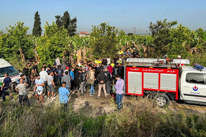 People gather at the site of an Israeli strike on a vehicle in the Adloun plain area, between Lebanon's southern cities of Sidon and Tyre, on April 23, 2024.