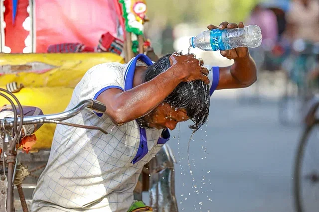 A rickshaw puller is pouring water on the head due to scorching heat.