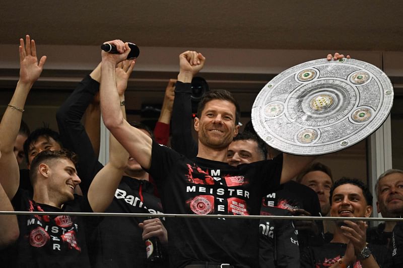 Bayer Leverkusen's Spanish head coach Xabi Alonso celebrates with a mock-up of the Bundesliga trophy with his players after the German first division Bundesliga football match Bayer 04 Leverkusen v Werder Bremen in Leverkusen, western Germany, on 14 April, 2024