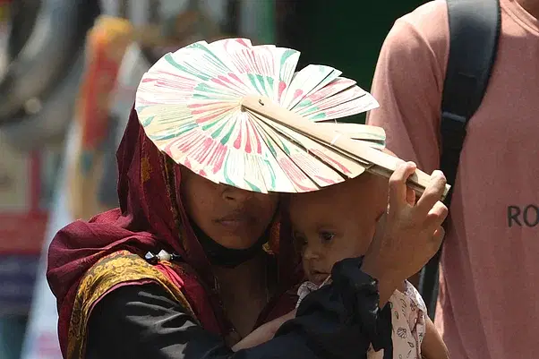 A woman protects her child with a handfan at Shaheed AHM Kamaruzzaman Square in Rajshahi on 24 April, 2024