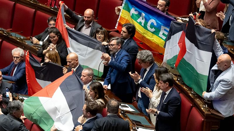 Several MPs from Italy's opposition Five Star Movement brandish five Palestinian flags and a peace flag in the lower Chamber of Deputies on May 28, 2024 in Rome's Montecitorio palace during a discussion on the Middle East crisis, as their colleague Riccardo Ricciardi speaks, calling on Italy to recognise the state of Palestine