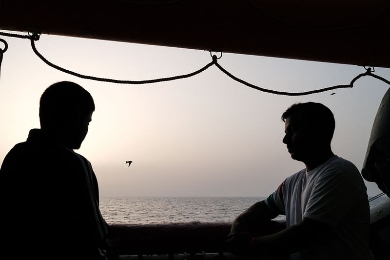 Migrants look at at sunset onboard the Ocean Viking rescue ship of European maritime-humanitarian organization "SOS Mediterranee" following a rescue operation off Malta, early on 20 May 2024.