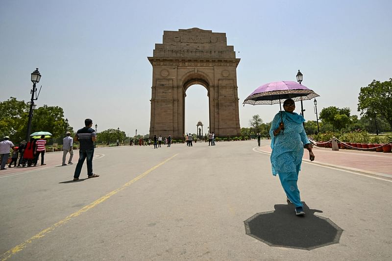 A woman holding an umbrella walks near the India Gate during severe heatwave on a hot summer day in New Delhi on 29 May 2024.