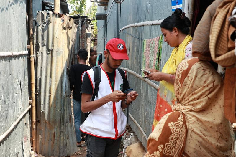 A Bangladesh Red Crescent volunteer is talking with a slum resident in Dhaka city. The assessment was done to collect data of vulnerable people affected by heatwave in Bangladesh. Dhaka, Bangladesh 2024