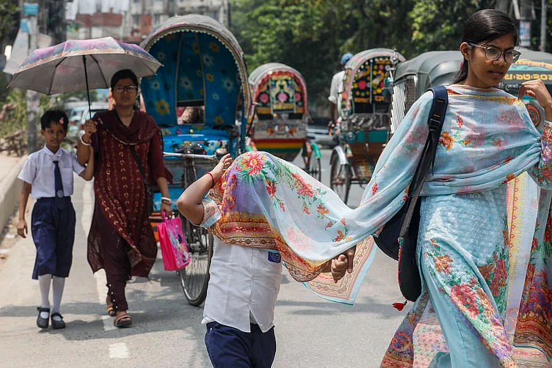 A child protects himself from scorching sun taking shelter under the dupatta of his mother in Nandan area, Chattogram on 15 May, 2024