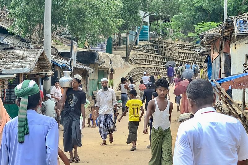 This photo taken on 24 May 2024 shows Rohingya refugees walking down a path at a Rohingya refugee camp in Ukhia in Bangladesh's southeastern Cox's Bazar district.