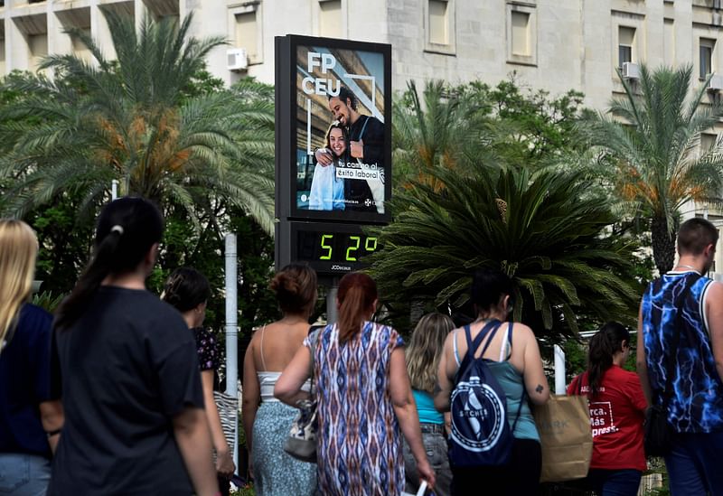 Pedestrians walk past a temperature street sign showing a locally 52 degrees Celsius during a heatwave in Seville on 10 July, 2023.