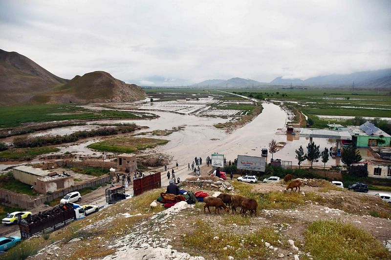 Afghan people gather along a road before a flooded area between Samangan and Mazar-i-Sharif following a flash flood after a heavy rainfall in Feroz Nakhchir district of Samangan Province on 11 May, 2024