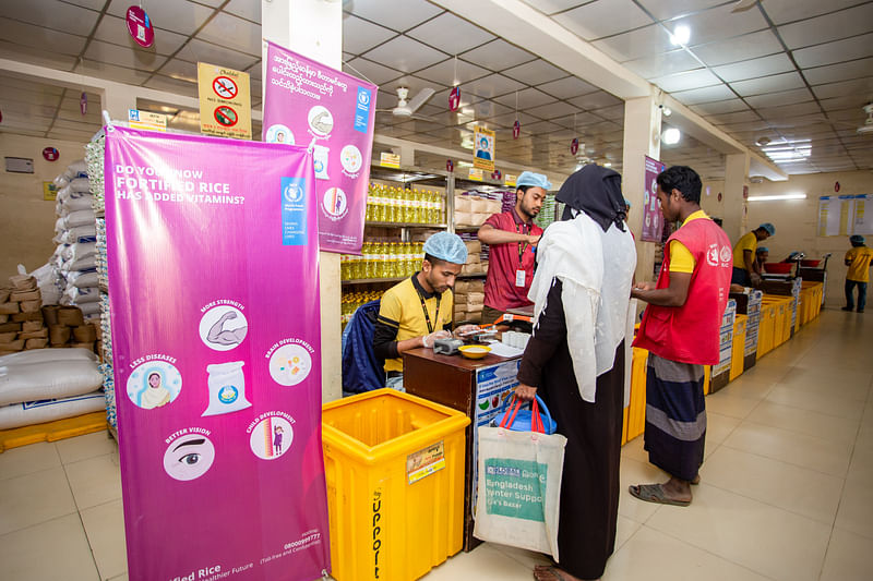 Caption: The Rohingya collect their monthly food ration at a World Food Programme (WFP) e-voucher outlet in Cox’s Bazar. Starting June 2024, WFP will increase the ration to USD 11 with locally fortified rice in its food assistance package.