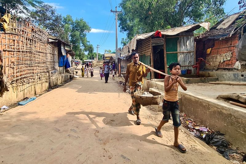 This photo taken on 24 May, 2024 shows Rohingya refugees walking down a path at a Rohingya refugee camp in Ukhia in Bangladesh's southeastern Cox's Bazar district