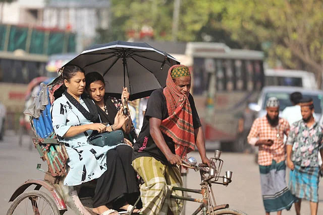 Two people with an umbrella in a rickshaw amid the heatwave. The picture was taken from Mohammadpur area in the capital on Friday.