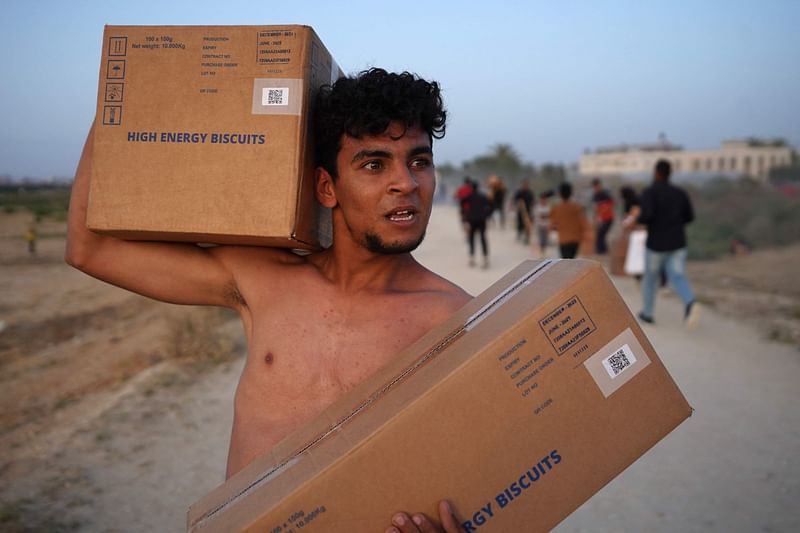 A Palestinian carries boxes of humanitarian aid after rushing the trucks transporting the international aid from the US-built Trident Pier near Nuseirat in the central Gaza Strip on 18 May 2024, amid the ongoing conflict between Israel and the militant group Hamas.