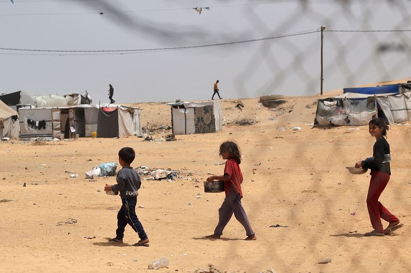 Displaced Palestinian children carry containers with food in Rafah, on the southern Gaza Strip, on 19 May, 2024, amid the ongoing conflict between Israel and the militant Hamas group.