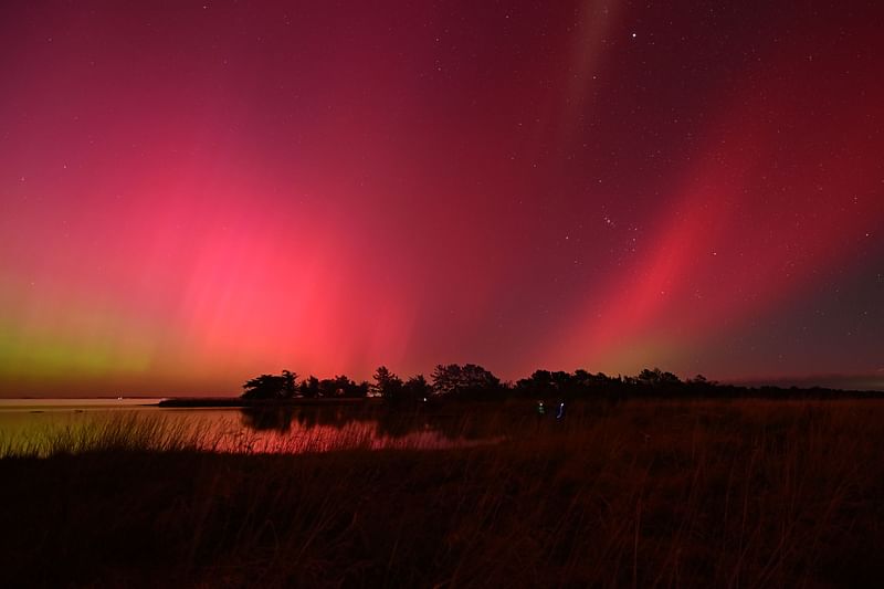 The Aurora Australis, also known as the Southern Lights, glow on the horizon over waters of Lake Ellesmere on the outskirts of Christchurch on 11 May, 2024