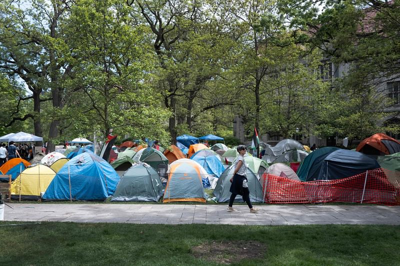 A woman walks past a protest encampment on the University of Chicago campus on May 04, 2024 in Chicago, Illinois. More than 2,000 people have been arrested nationwide as students at colleges and universities around the country have staged protests and encampments calling for a ceasefire in Gaza