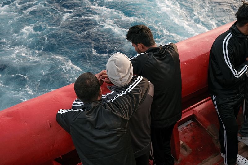 Migrants look at the sea from the main deck of the Ocean Viking rescue ship of European maritime-humanitarian organization "SOS Mediterranee" following a rescue operation off Malta, early on 20 May 2024.