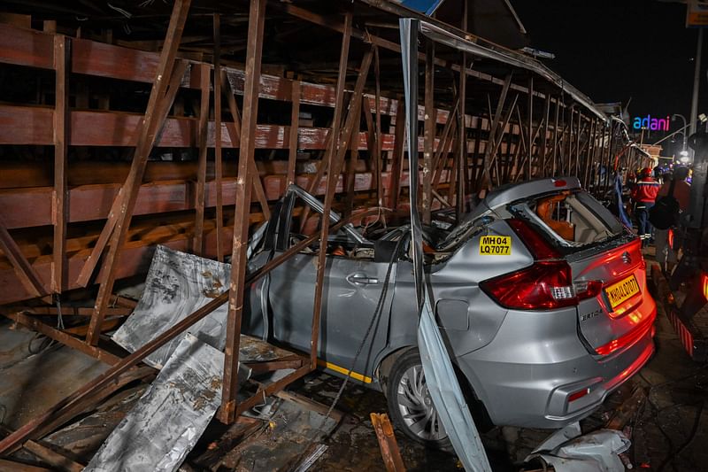 This photograph shows a heavily damaged car at the site where an advertisement billboard collapsed at a petrol station following a dust storm in Mumbai on May 13, 2024.