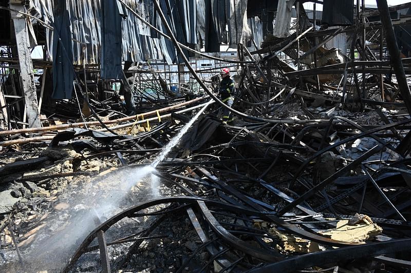 An employee of the State Emergency Service of Ukraine sprays water on debris in a hardware supermarket in Kharkiv destroyed by a Russian strike, on 26 May, 2024, amid the Russian invasion in Ukraine