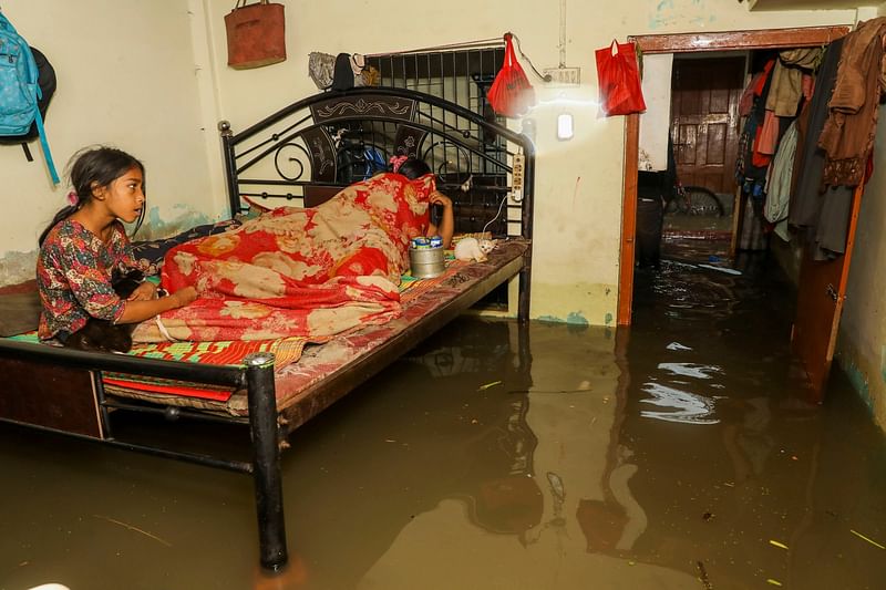 A girl holding her cat sits on the bed as water inundates their house in Chattogram, Bangladesh on 27 May 2024.
