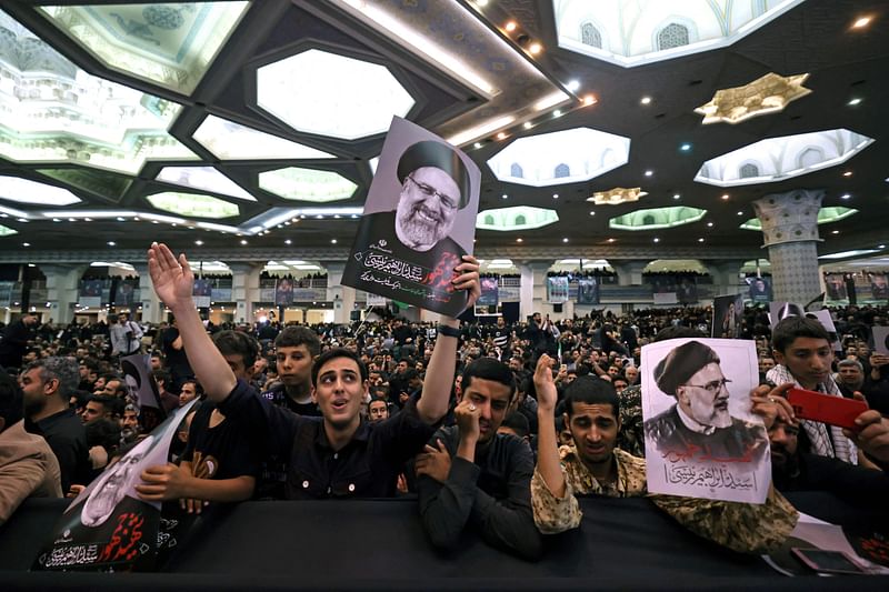 Mourners hold posters of late Iranian President Ebrahim Raisi during a funeral ceremony for him and his companions who were killed in a helicopter crash at Mosalia mosque in Tehran, on May 21, 2024