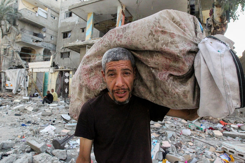 A Palestinian man carries his belongings at the site of an Israeli strike on a house, in Rafah, in the southern Gaza Strip on 20 May, 2024