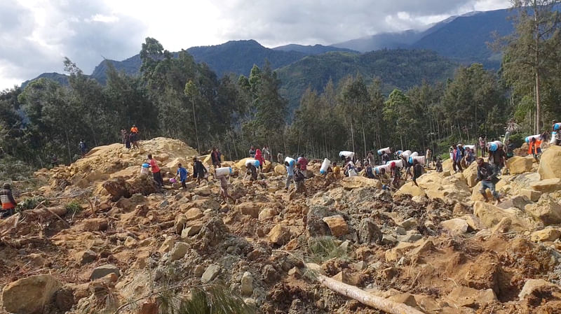 People carry bags in the aftermath of a landslide in Enga Province, Papua New Guinea, May 24, 2024, in this still image obtained from a video