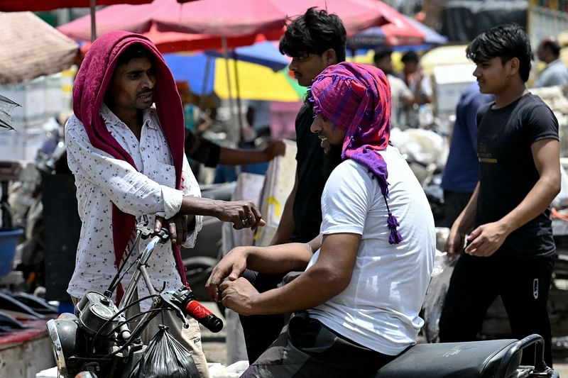 Men cover their head with cloth on a hot summer afternoon in New Delhi on 29 May, 2024.