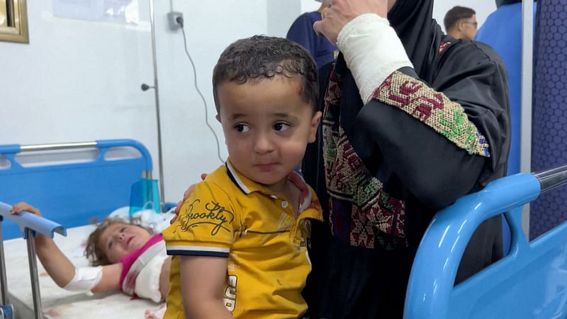 A Palestinian woman holds a child as people are assisted at a hospital following an Israeli strike on an area designated for displaced people, as the war in Gaza continues, in Rafah in the southern Gaza Strip, on 26 May, 2024, in this screen grab from a video obtained by Reuters