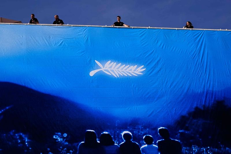 Workers hang the official poster of the 77th Cannes Film Festival on the facade of the Palais des Festivals in Cannes, south-eastern France, on 12 May, 2024. Cannes Film festival will take place from 14 to 25 May.