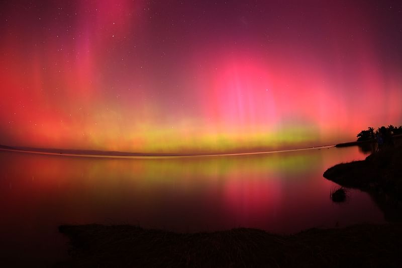 The Aurora Australis, also known as the Southern Lights, glow on the horizon over waters of Lake Ellesmere on the outskirts of Christchurch on 11 May, 2024. The most powerful solar storm in more than two decades struck Earth, triggering spectacular celestial light shows from Tasmania to Britain -- and threatening possible disruptions to satellites and power grids as it persists into the weekend.